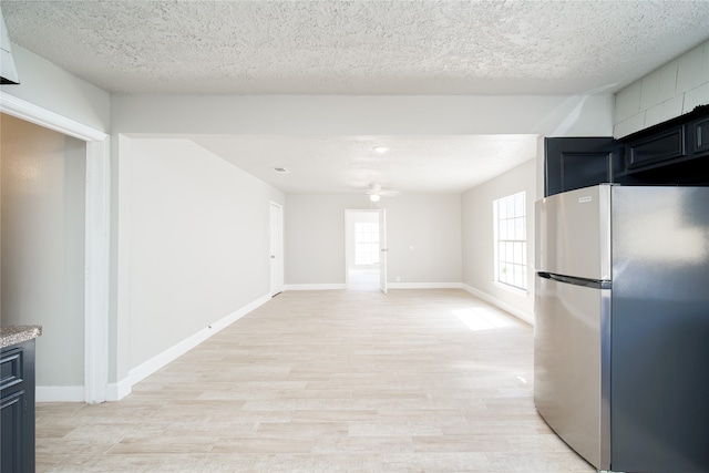 kitchen with a textured ceiling, light hardwood / wood-style floors, and stainless steel fridge