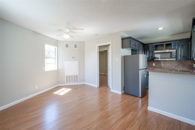 kitchen with appliances with stainless steel finishes, hardwood / wood-style floors, ceiling fan, and tasteful backsplash