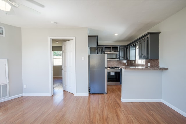 kitchen with ceiling fan, appliances with stainless steel finishes, backsplash, and light hardwood / wood-style flooring