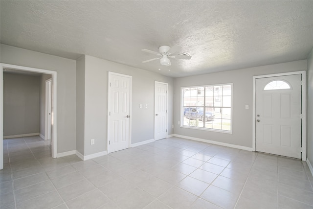 entrance foyer with a textured ceiling, light tile patterned flooring, and ceiling fan