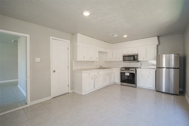 kitchen with white cabinets, a textured ceiling, appliances with stainless steel finishes, and sink