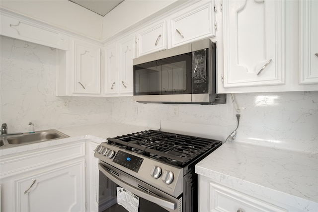 kitchen with appliances with stainless steel finishes, sink, and white cabinets