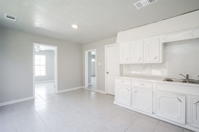 kitchen featuring white cabinetry, a textured ceiling, light tile patterned flooring, and sink