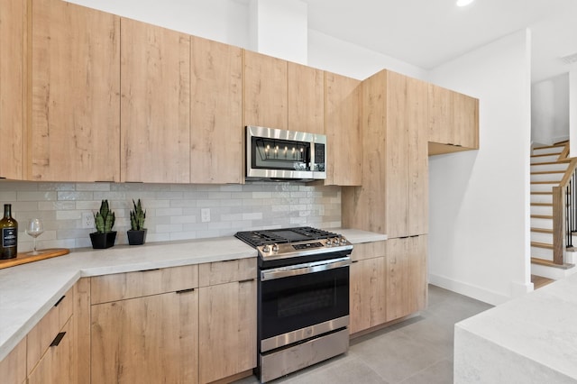 kitchen featuring appliances with stainless steel finishes, decorative backsplash, and light brown cabinetry