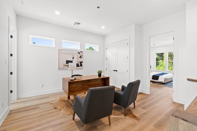 office with light wood-type flooring and plenty of natural light