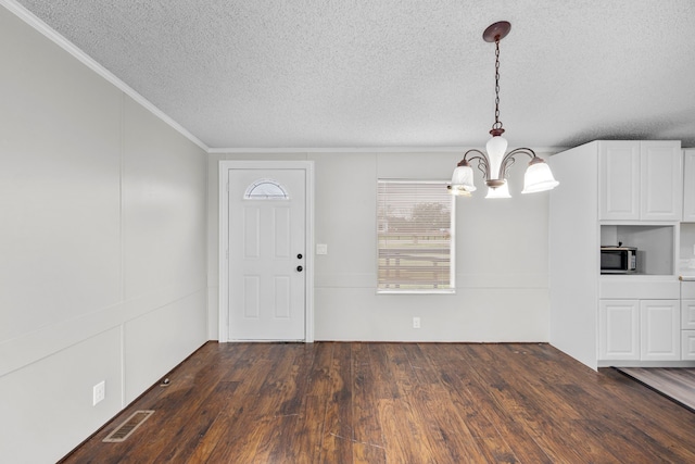 entrance foyer featuring a textured ceiling, crown molding, dark wood-type flooring, and a chandelier