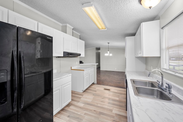 kitchen with black fridge, sink, white cabinetry, crown molding, and light hardwood / wood-style floors