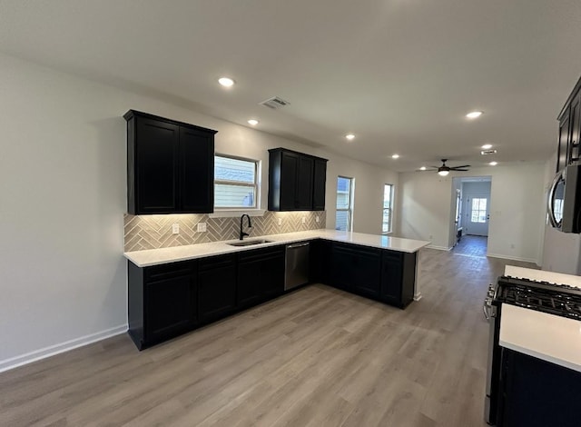 kitchen with a sink, stainless steel dishwasher, gas range oven, decorative backsplash, and dark cabinets