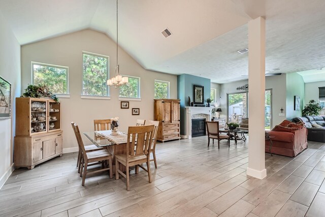 dining area featuring a glass covered fireplace, plenty of natural light, visible vents, and wood tiled floor