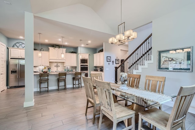 dining room with lofted ceiling, recessed lighting, an inviting chandelier, light wood finished floors, and baseboards