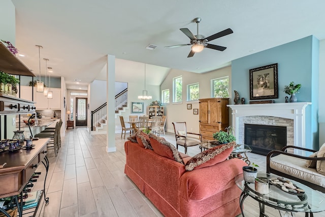 living room with ceiling fan with notable chandelier and vaulted ceiling