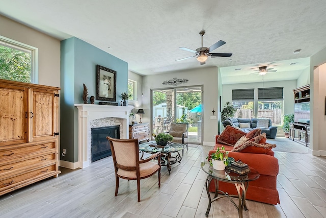 living room with ceiling fan, plenty of natural light, and a textured ceiling