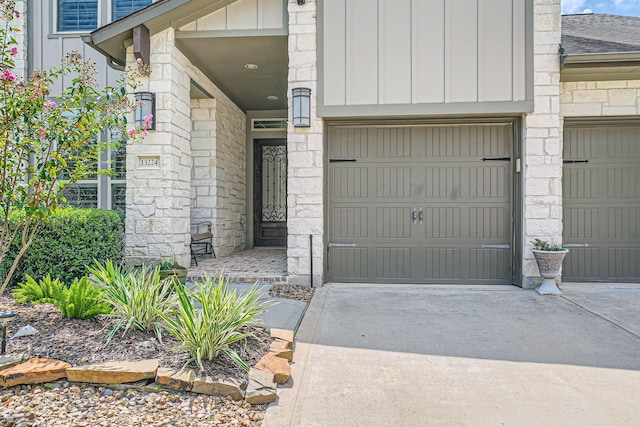 view of exterior entry featuring stone siding, board and batten siding, concrete driveway, and a shingled roof