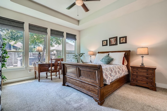 carpeted bedroom with ceiling fan and a tray ceiling