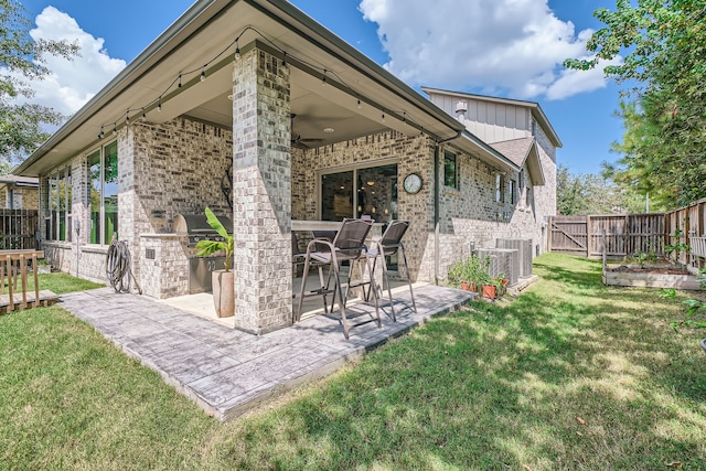 back of property featuring central air condition unit, a patio, ceiling fan, and a lawn