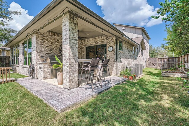 rear view of house featuring area for grilling, a fenced backyard, a yard, central AC unit, and a patio area