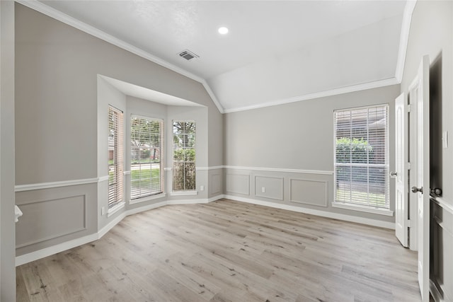 empty room with light hardwood / wood-style floors, crown molding, a wealth of natural light, and vaulted ceiling