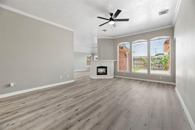 unfurnished living room with ceiling fan, light hardwood / wood-style floors, crown molding, and a brick fireplace