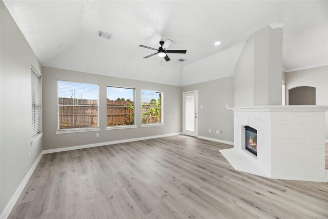 unfurnished living room with ceiling fan, lofted ceiling, a fireplace, and light hardwood / wood-style flooring