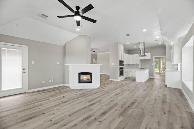 unfurnished living room with ceiling fan, light hardwood / wood-style flooring, and vaulted ceiling