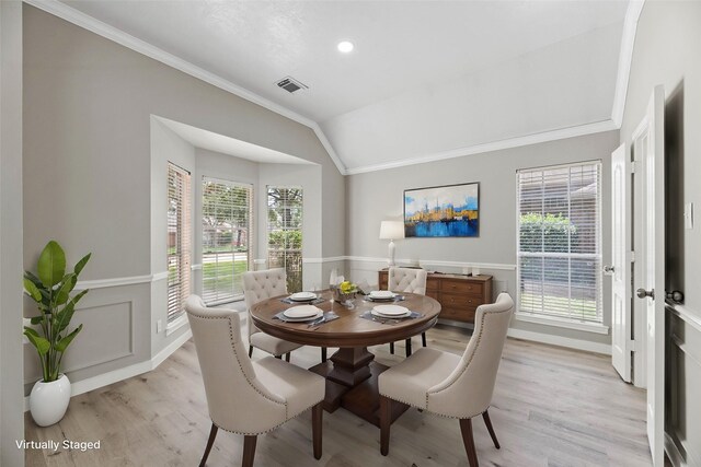 dining area with light hardwood / wood-style floors, crown molding, a wealth of natural light, and lofted ceiling