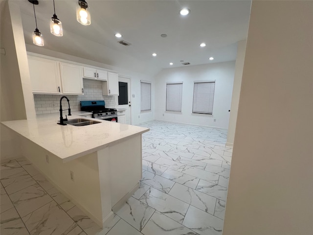 kitchen featuring sink, white cabinets, kitchen peninsula, decorative light fixtures, and stainless steel range