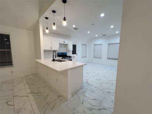 kitchen with white cabinets, kitchen peninsula, stainless steel range oven, decorative light fixtures, and sink