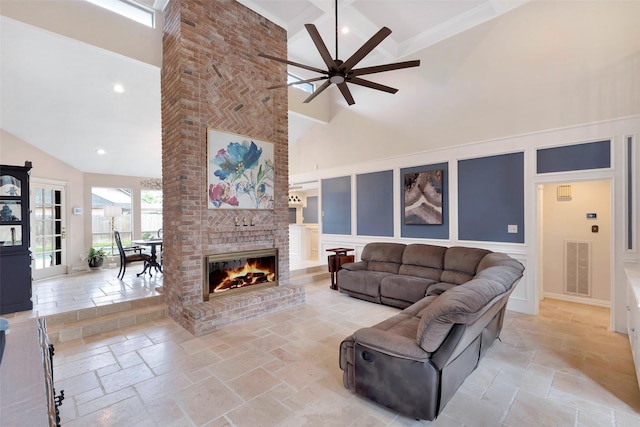 living room with visible vents, stone tile flooring, high vaulted ceiling, and a decorative wall