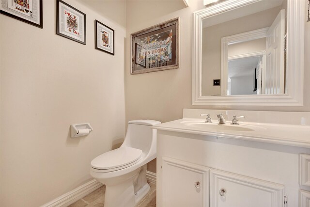 bathroom with tile patterned flooring, vanity, toilet, and baseboards