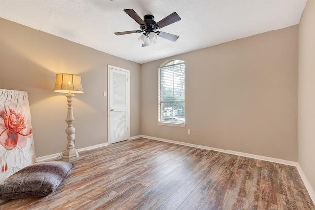 living area with baseboards, a ceiling fan, and wood finished floors