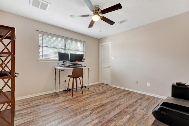 office space with wood finished floors, visible vents, a ceiling fan, and baseboards