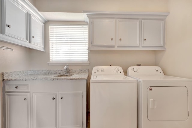 clothes washing area with cabinet space, independent washer and dryer, and a sink