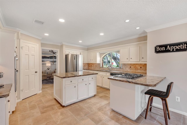 kitchen with white cabinets, a peninsula, visible vents, and freestanding refrigerator