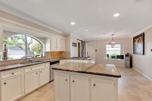 kitchen with stainless steel appliances, stone tile flooring, a sink, dark stone counters, and a kitchen island
