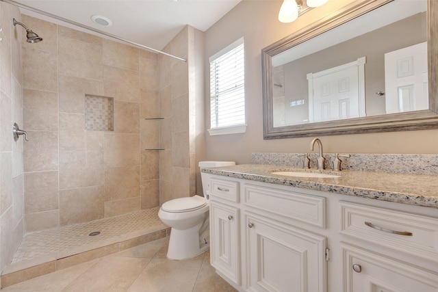 full bathroom featuring tiled shower, vanity, and toilet