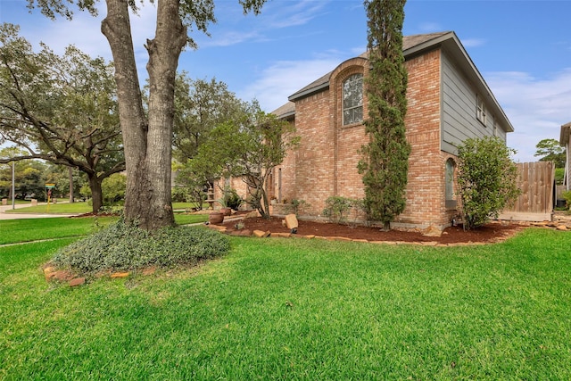 view of home's exterior featuring brick siding and a yard