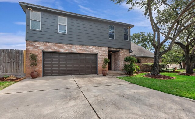 view of front of house with a front lawn, driveway, fence, brick siding, and an attached garage