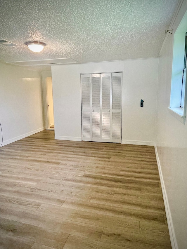 unfurnished room with a textured ceiling and wood-type flooring