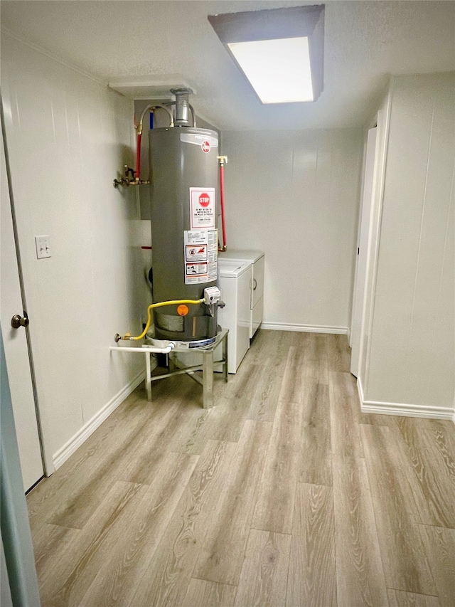 interior space with gas water heater, light hardwood / wood-style floors, washer and dryer, and a textured ceiling