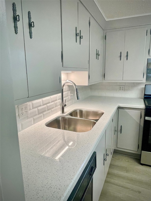 kitchen featuring dishwasher, sink, stove, light hardwood / wood-style flooring, and light stone countertops