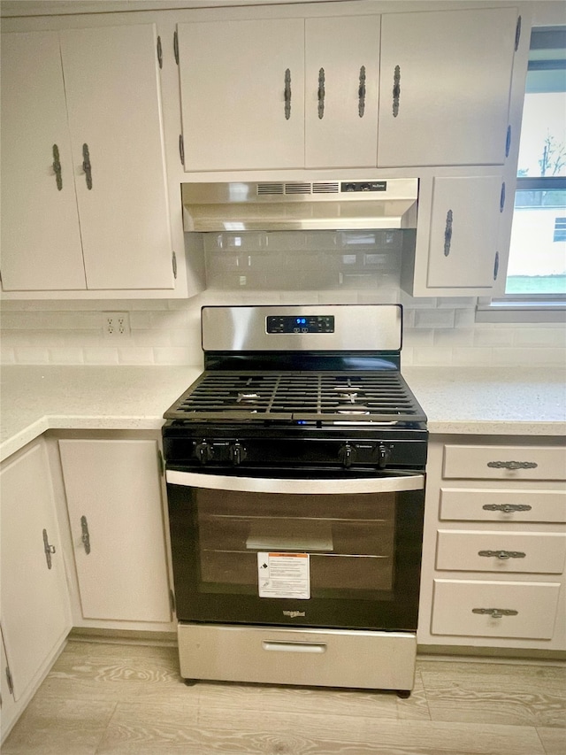 kitchen with white cabinets, backsplash, stainless steel gas range, and extractor fan