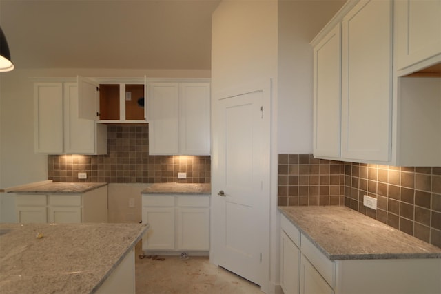 kitchen featuring light stone countertops, decorative backsplash, and white cabinets