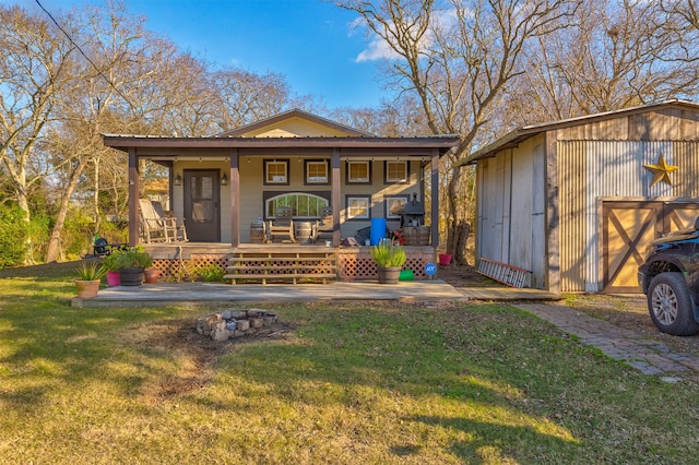 view of front of home featuring covered porch, a front yard, and an outbuilding