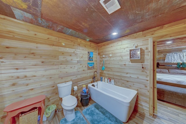 bathroom featuring wood-type flooring, a bathing tub, wood walls, and toilet