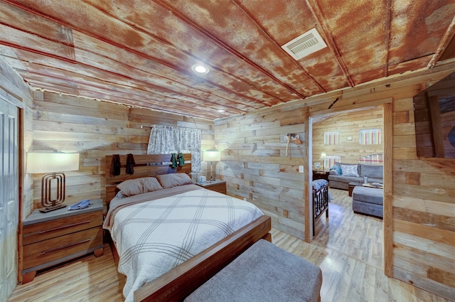 bedroom with wooden walls and light hardwood / wood-style flooring