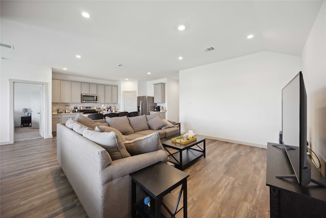 living room featuring light hardwood / wood-style flooring and vaulted ceiling