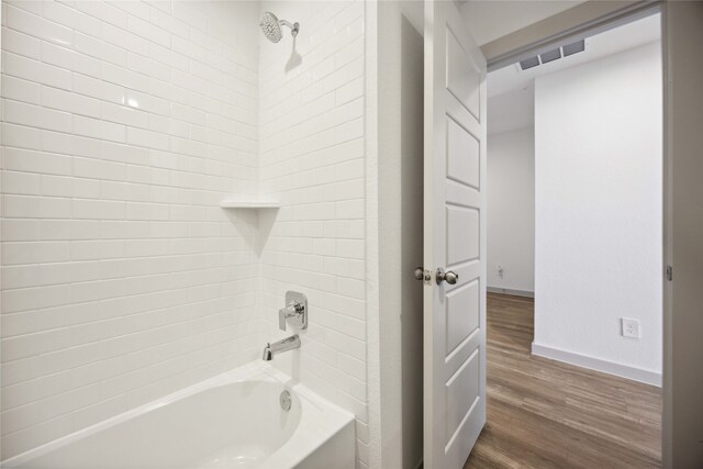 bathroom with tiled shower / bath combo and hardwood / wood-style floors