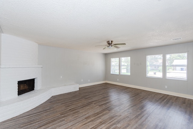 unfurnished living room with ceiling fan, dark hardwood / wood-style floors, a fireplace, and a textured ceiling