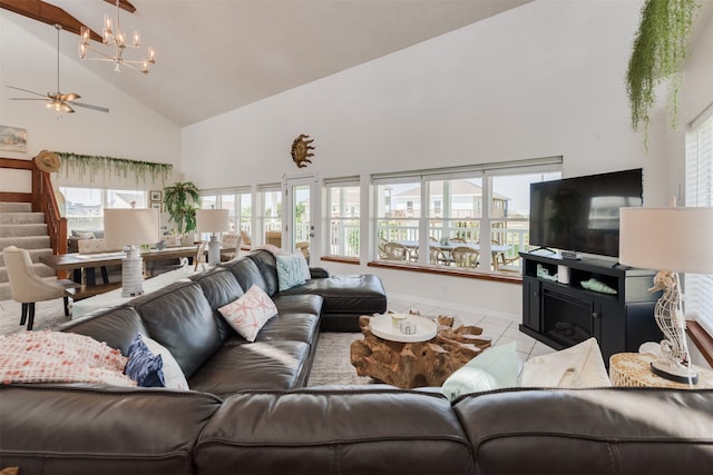 living room with light tile patterned flooring, ceiling fan with notable chandelier, and high vaulted ceiling