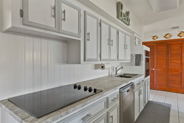 kitchen featuring light tile patterned flooring, white cabinetry, dishwasher, sink, and black electric stovetop